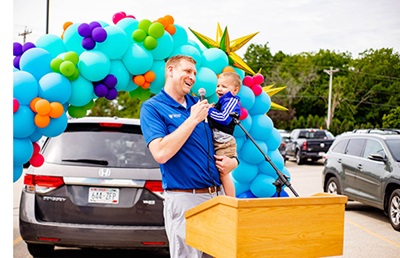Man holding a baby giving a speech.